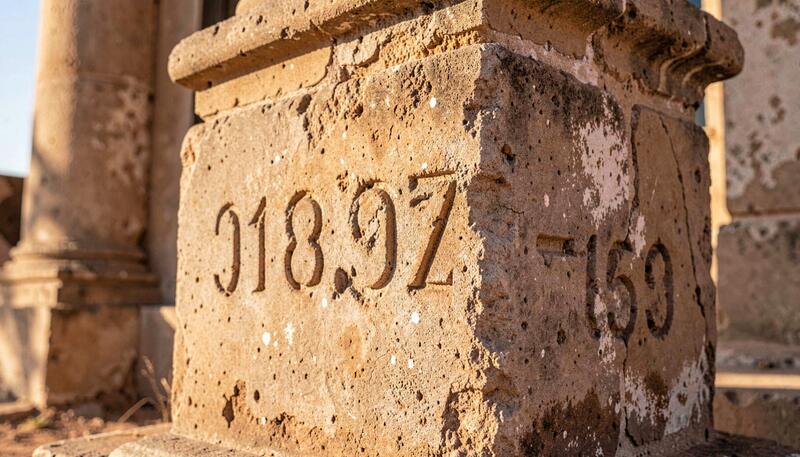 Weathered church cornerstone with carved date numerals in warm desert light
