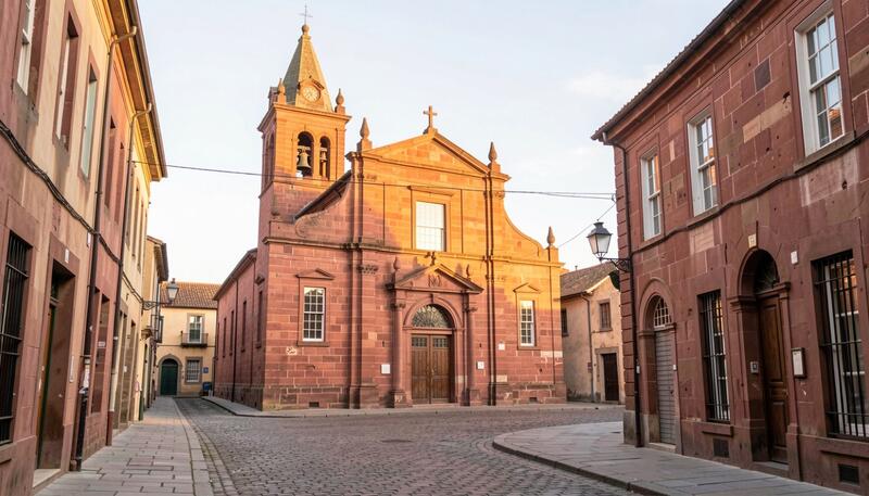 Red sandstone church facade with a bell tower on a quiet nineteenth century street in morning light